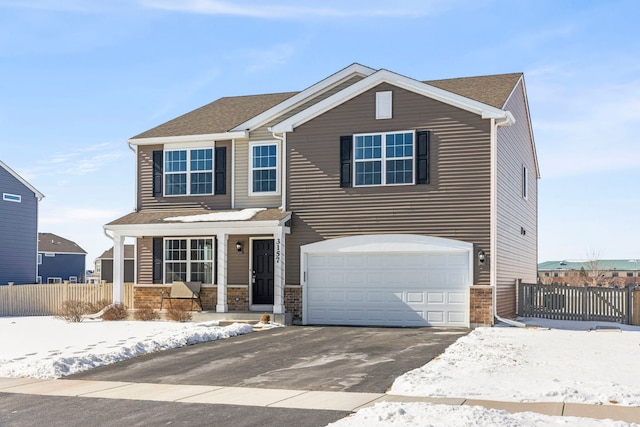 view of front facade featuring a garage, driveway, a porch, and fence