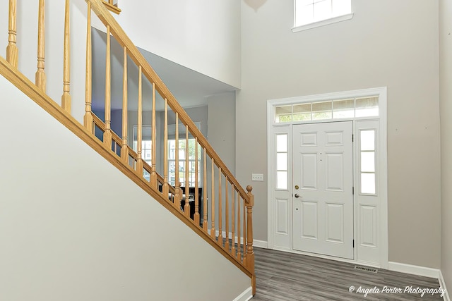 entryway with a towering ceiling and dark wood-type flooring