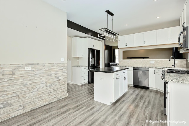 kitchen featuring white cabinetry, decorative light fixtures, a kitchen island, stainless steel appliances, and light hardwood / wood-style floors