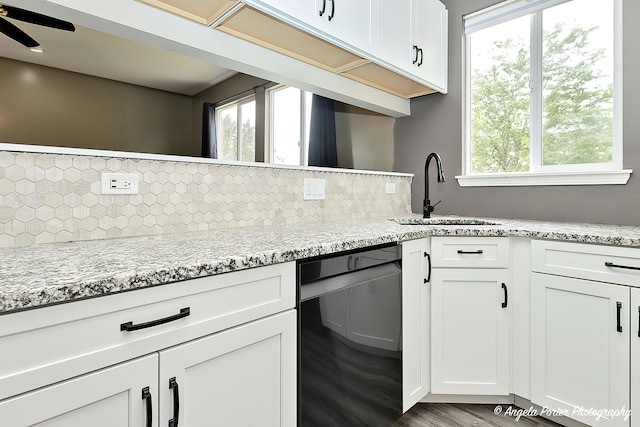 kitchen featuring sink, white cabinetry, light stone countertops, light hardwood / wood-style floors, and decorative backsplash