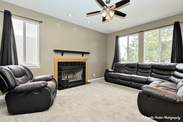 carpeted living room featuring a tiled fireplace, vaulted ceiling, and ceiling fan