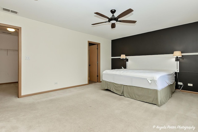 carpeted bedroom with ceiling fan, a walk in closet, and a closet