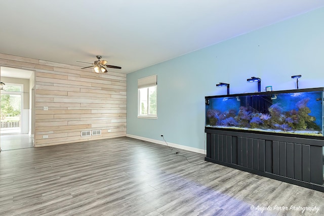 living room featuring ceiling fan, wooden walls, and wood-type flooring