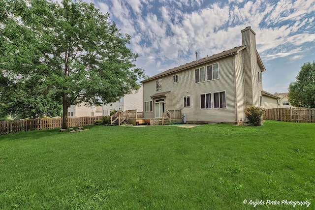 back of property featuring a wooden deck and a yard