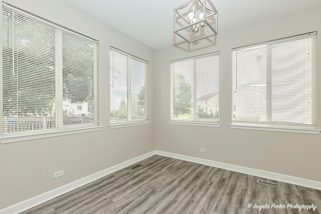 unfurnished room featuring hardwood / wood-style flooring and a chandelier