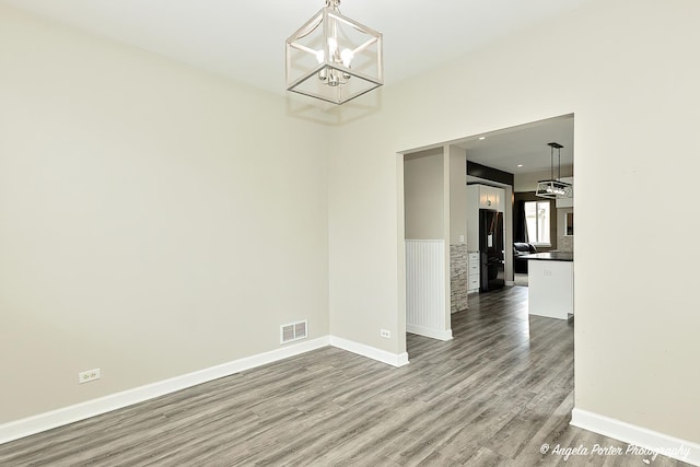 unfurnished dining area featuring an inviting chandelier and wood-type flooring