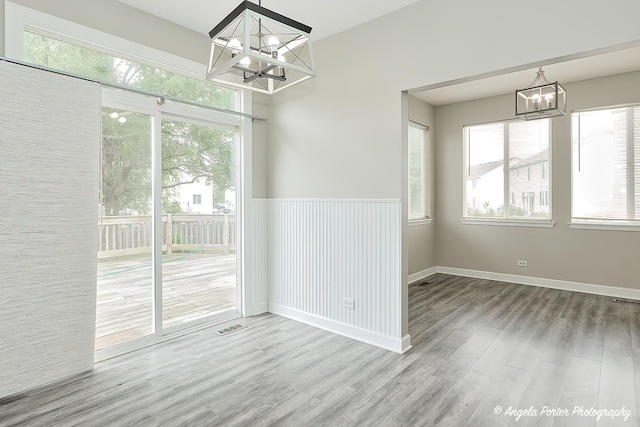 unfurnished dining area with wood-type flooring and a chandelier