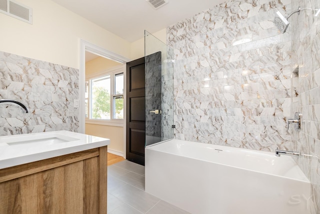 bathroom with tile walls, sink, tile patterned flooring, and a tub to relax in