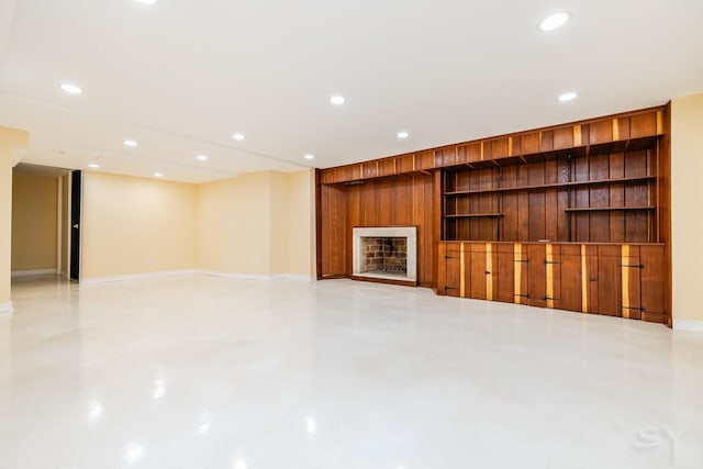 unfurnished living room with built in features and wooden walls