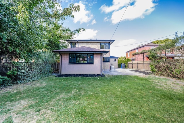 rear view of property featuring a lawn and a patio area