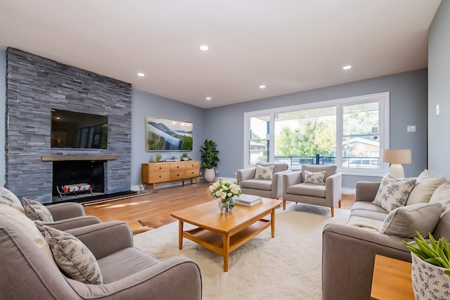 living room with a stone fireplace and light hardwood / wood-style flooring