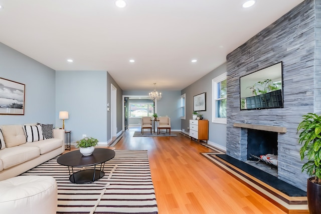 living room featuring a notable chandelier, a fireplace, and light hardwood / wood-style floors