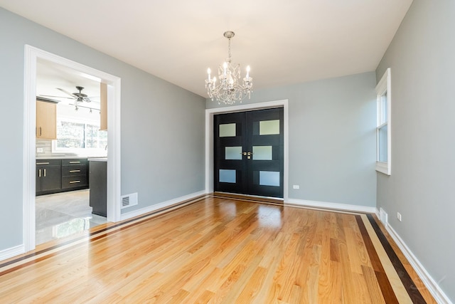 foyer with a notable chandelier, light hardwood / wood-style floors, and french doors