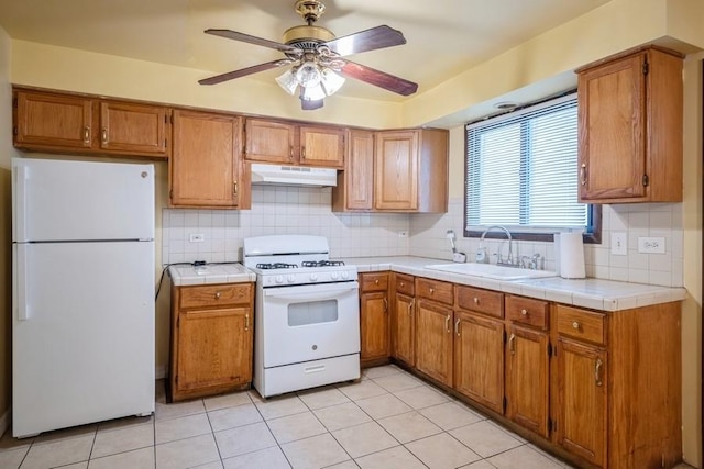 kitchen with sink, white appliances, ceiling fan, tile counters, and decorative backsplash