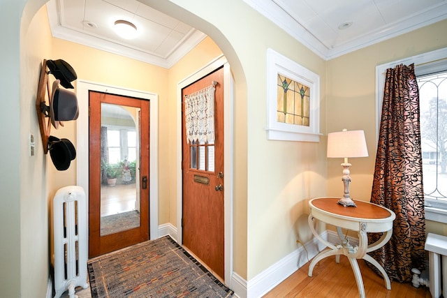 entrance foyer with radiator, crown molding, and wood-type flooring