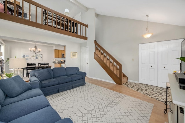 living room featuring an inviting chandelier, high vaulted ceiling, beam ceiling, and light hardwood / wood-style floors