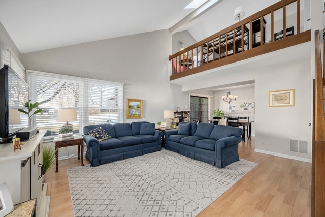 living room featuring beam ceiling, a chandelier, high vaulted ceiling, and light wood-type flooring