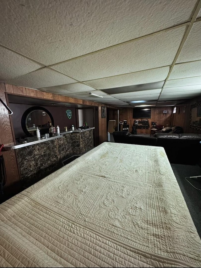 interior space featuring a paneled ceiling and wooden walls