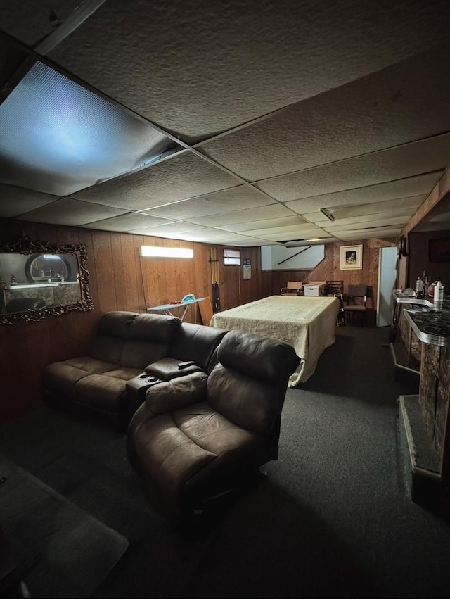 carpeted bedroom featuring a paneled ceiling and wooden walls