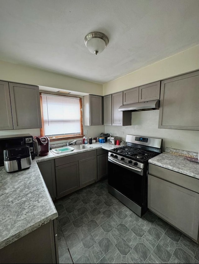 kitchen featuring gray cabinets, stainless steel gas range oven, and sink