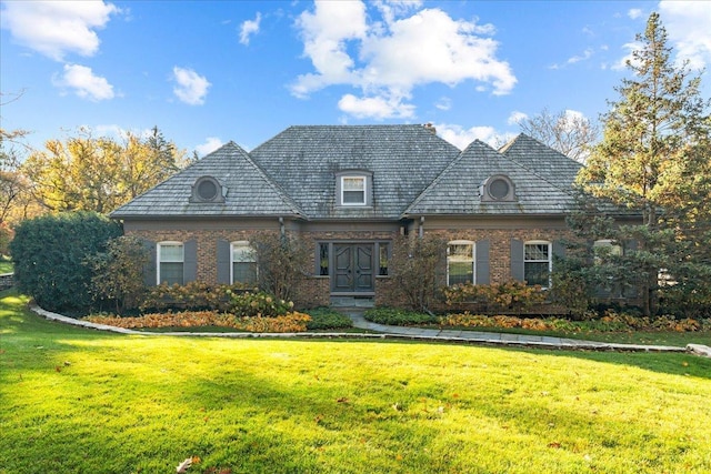 french country inspired facade featuring a front yard and brick siding