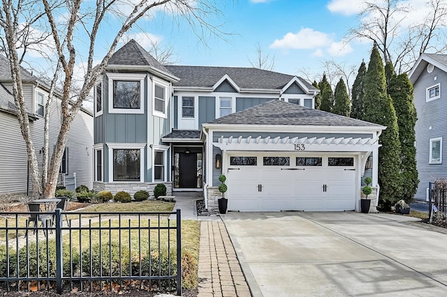 view of front of home featuring a shingled roof, concrete driveway, a front lawn, board and batten siding, and an attached garage