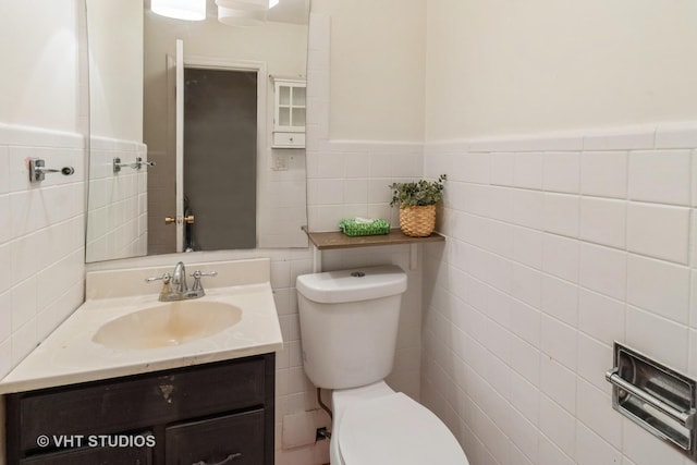 bathroom with vanity, tile walls, and toilet