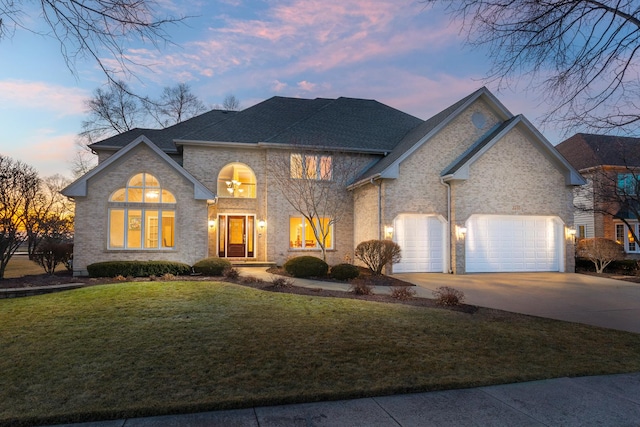 view of front facade with driveway, an attached garage, and a yard