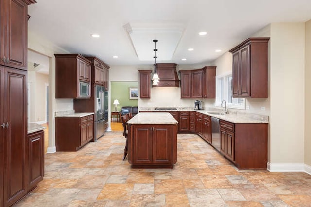 kitchen featuring custom range hood, appliances with stainless steel finishes, a center island, light countertops, and a sink