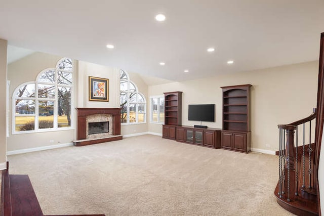 carpeted living room featuring vaulted ceiling, a glass covered fireplace, and a wealth of natural light