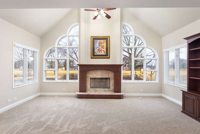 unfurnished living room with baseboards, ceiling fan, carpet floors, a fireplace, and high vaulted ceiling