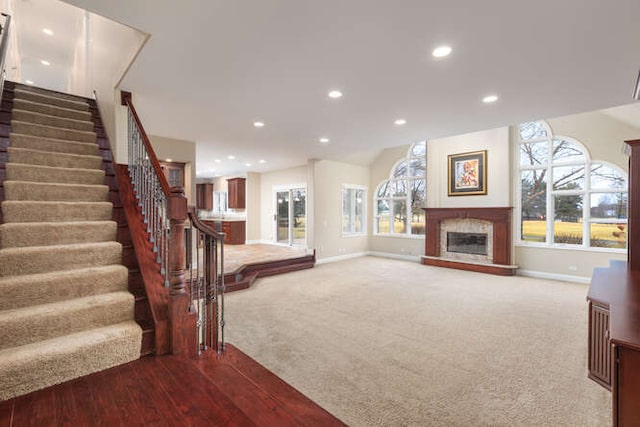 carpeted living room with recessed lighting, plenty of natural light, and a glass covered fireplace