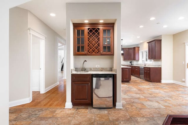 kitchen with dishwasher, glass insert cabinets, light countertops, a sink, and recessed lighting