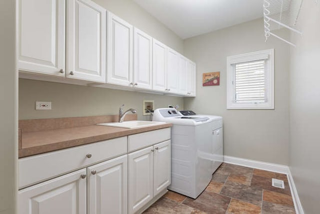 laundry area with cabinet space, stone finish flooring, a sink, washer and dryer, and baseboards