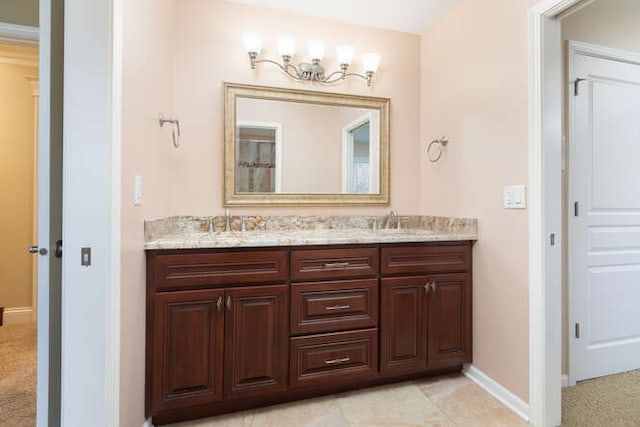 full bath with double vanity, a sink, and baseboards