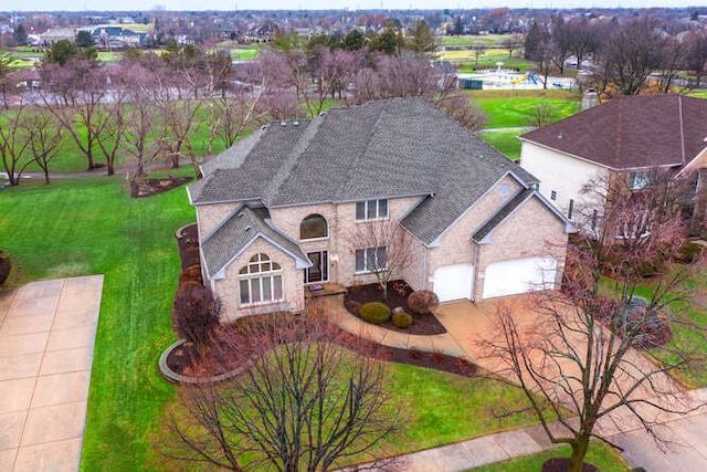 view of front facade with a garage, stone siding, driveway, roof with shingles, and a front lawn