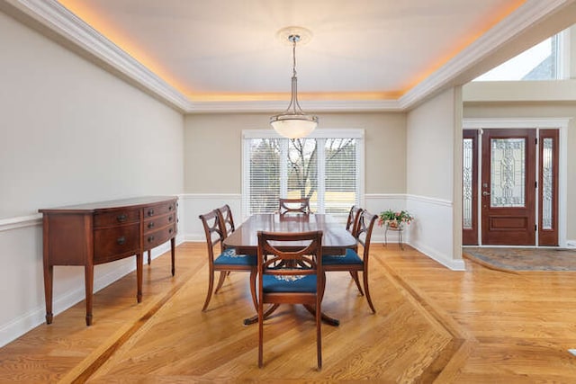 dining area with a tray ceiling, baseboards, and light wood finished floors