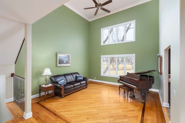 living area featuring baseboards, a ceiling fan, ornamental molding, wood finished floors, and high vaulted ceiling