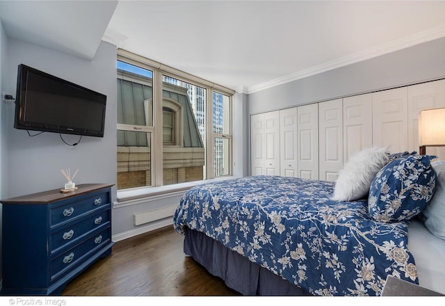 bedroom featuring dark wood-type flooring, ornamental molding, and a closet