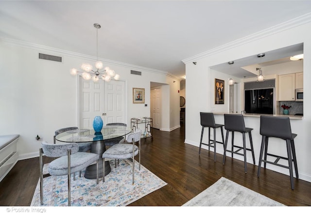 dining area with dark hardwood / wood-style flooring, ornamental molding, and a chandelier