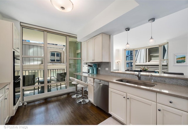 kitchen featuring dishwasher, white cabinetry, sink, dark hardwood / wood-style flooring, and hanging light fixtures