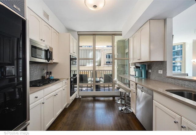 kitchen featuring floor to ceiling windows, appliances with stainless steel finishes, dark hardwood / wood-style floors, decorative backsplash, and white cabinets