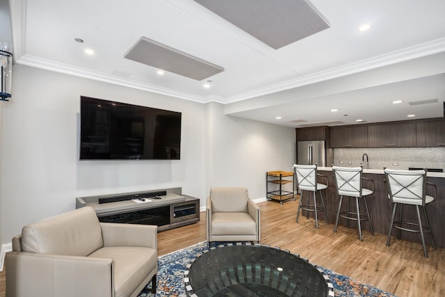 living room with crown molding, sink, and light hardwood / wood-style floors