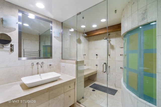 bathroom featuring tile walls, vanity, tasteful backsplash, and a shower with door