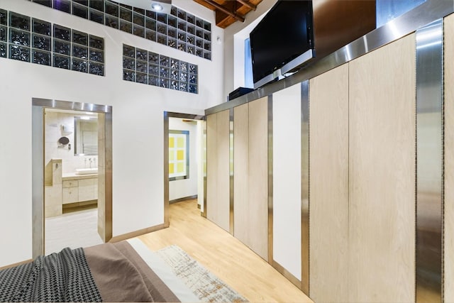 hall featuring a towering ceiling and light hardwood / wood-style flooring