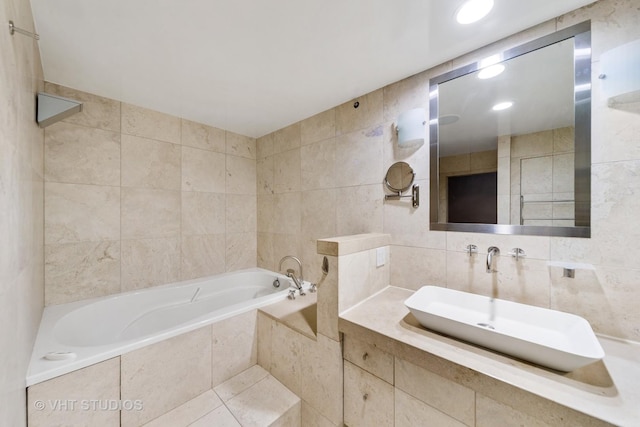 bathroom featuring tile walls, sink, and a relaxing tiled tub