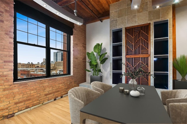 dining room with beamed ceiling, wood ceiling, brick wall, and wood-type flooring