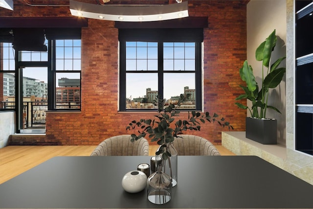 dining space featuring hardwood / wood-style flooring, brick wall, and a high ceiling