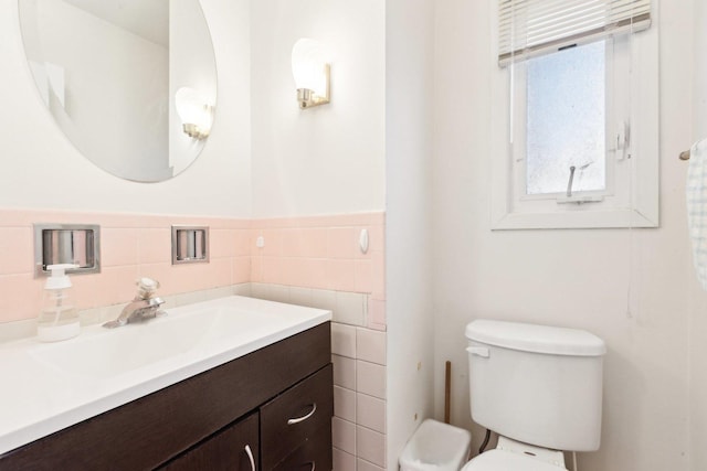 bathroom featuring tile walls, wainscoting, vanity, and toilet