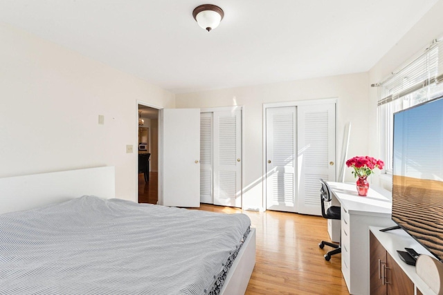 bedroom with light wood-style flooring and two closets